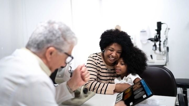 A mother and her child speaking with a doctor in his office. 