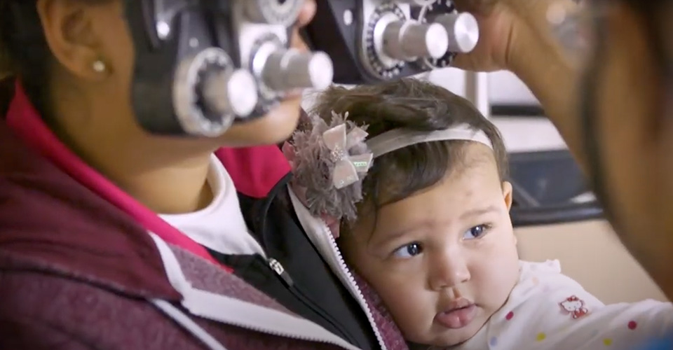 A patient with a baby receiving an eye exam